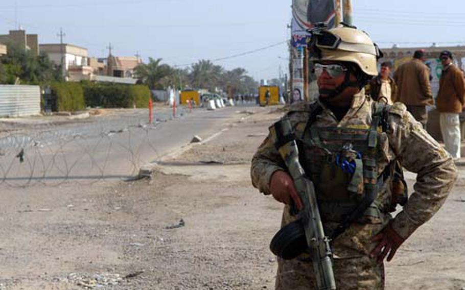 Pfc. Jalal Hassan guards the entrance to a Baghdad polling site Saturday. The lack of election day attacks boosted Iraqi army morale and won over Iraqi civilians.