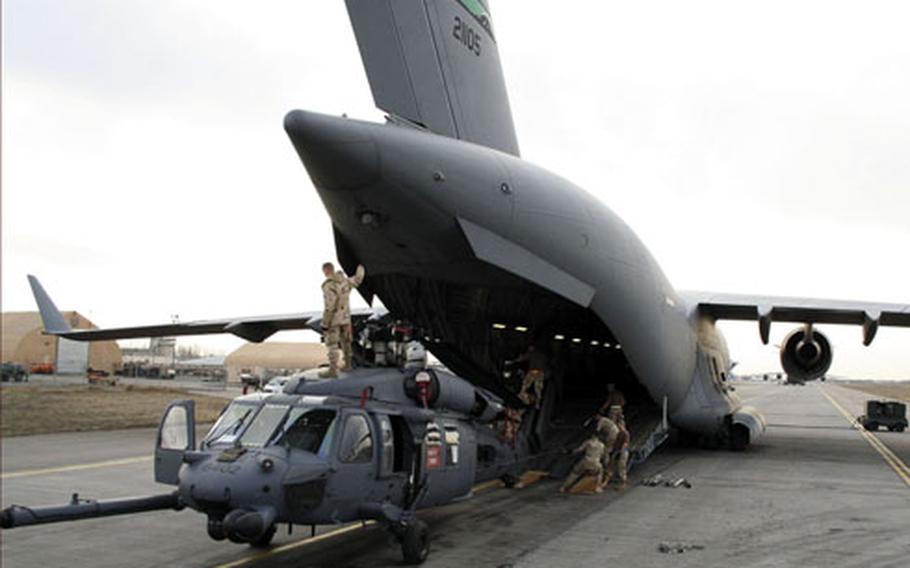 Air Force personnel work with maintainers to load a Black Hawk helicopter into a C-17 Globemaster III at Manas Air Base, Kyrgyzstan.