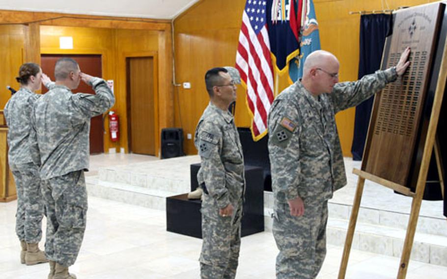 Lt. Col. James Carter, right, chaplain of the 4th Infantry Division and Multi-National Division – Baghdad, reaches out to touch the memorial plaque honoring 94 soldiers killed during the division’s 15-month deployment in Iraq.
