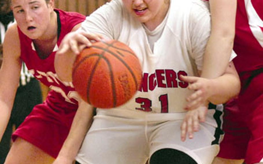 Lakenheath Lady Lancer Lisa McBride dribbles past Barbara Burriss and Karah Helm of Kaiserslautern during a battle of Division I foes during a Jan. 24 game in Kaiserslautern, Germany. Lakenheath defeated previously unbeaten Kaiserslautern 46-40 in overtime.