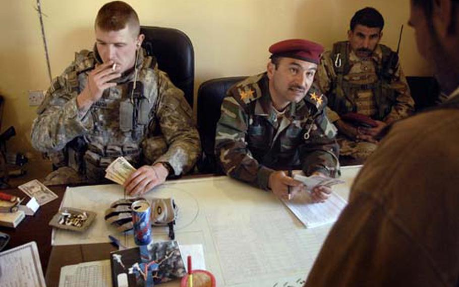 Sgt. Brandon Waugh, with Company B, 1st Battalion, 2nd Infantry Regiment, pauses in the middle of passing out $50 bills to an Iraqi army officer to pay “Sons of Iraq” members their final U.S.-backed paychecks at a school near Iskandariyah, Iraq.