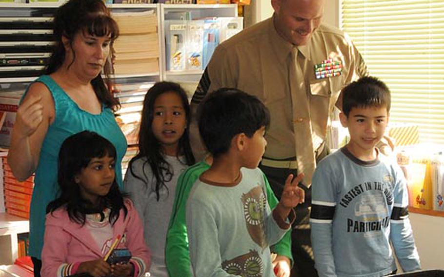 Markie Bonar, left, Marine Thrift Shop manager, and Master Sgt. Mike Hansen talk with students at AmerAsian School in Okinawa on Thursday, a school in Ginowan City for children of American-Japanese descent. Thrift shop officials donated $4,000 to the school to be used for scholarships for less-privileged children to pay for school tuition.