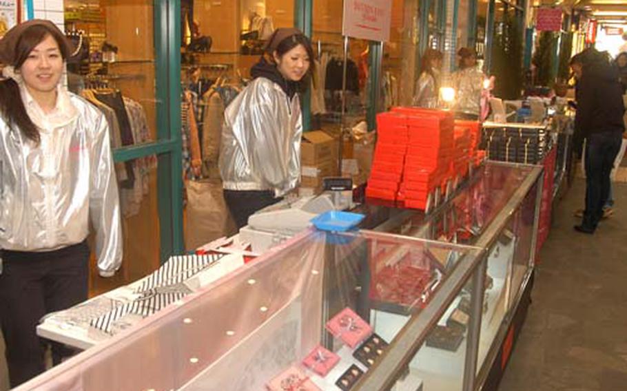 Saleswomen stand by to wrap boxes of chocolate at a row of Valentine's Day booths in the More's building next to Yokosuka Chuo Station in Yokosuka, Japan, on Thursday. For Valentine's Day in Japan, women purchase chocolates for men.