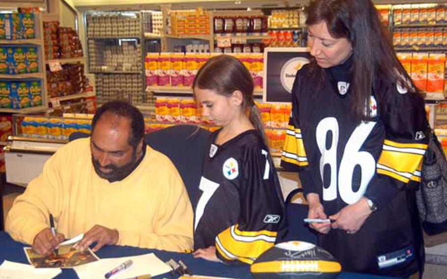 Jerrilyn Ishee, right, and her daughter, Audrey, get autographs from NFL Hall of Famer Franco Harris at the Yokosuka Naval Base, Japan, commissary Thursday. Harris is touring bases throughout the Asian theater as part of a California Sunshine tour.