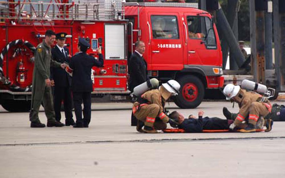 Okinawa prefectural police interview a U.S. Navy aircrew member Wednesday, as Uruma City firefighters tend to injured sailors during a mock emergency response drill at White Beach Naval Facility in Okinawa, Japan.