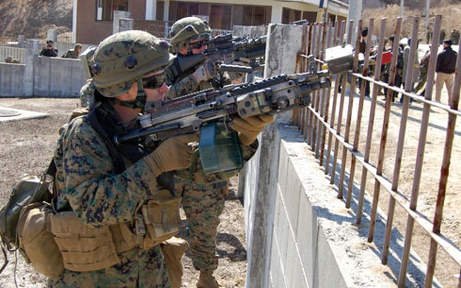 Marines from L Company, 3rd Battalion, 5th Marine Regiment, place suppressive fire on a building while members of their unit practice clearing rooms Tuesday at Rodriguez Range.
