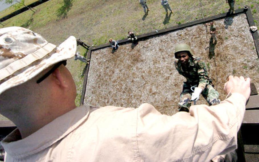 Marine Corps Staff Sgt. Peter Gruner, foreground, encourages Zama American High School student Treyvon Fowler as the JROTC cadet rappels down the 40-foot wall on the rappelling tower at the Corps&#39; Camp Fuji, Japan. For more photos, see thed link at the top of the story.