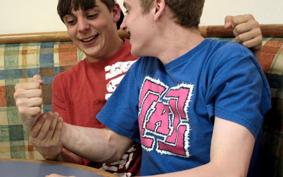 Chase Lumm, left, and Tim Eckles, right, both 15, compare muscles before an arm wrestling contest at the community center at RAF Lakenheath, England, where they attend high school. They have been friends for less than a year but have formed a close bond, one which they say helps them cope with life in the military community.