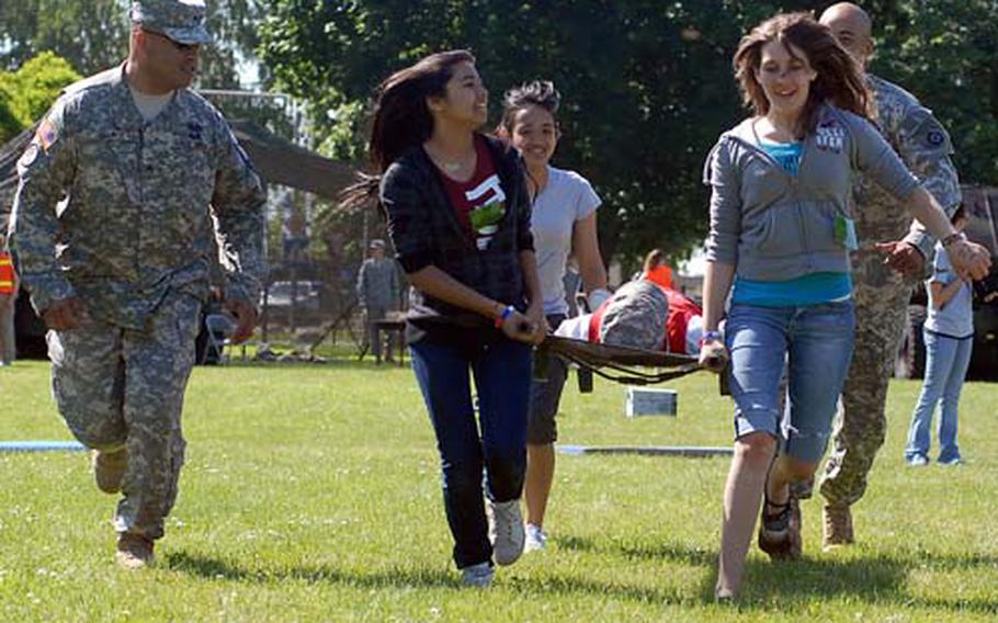Staff Sgt. Hector Campos, left, cheers on Keilani Penarejo, Djozelle Laureta, Erin Barshinger and Staff Sgt. Pablo Reid, as they carry James Da in a stretcher race.