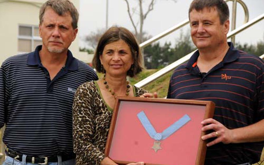 Jim Carlson, left, Janie Brady, middle, and Jeff Carlson hold up 4th Marine Regiment&#39;s Medal of Honor for Pfc. Albert E. Schwab at Camp Schwab Sunday. The three, the niece and nephews of Schwab were visiting the base for the first time.