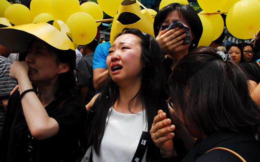 Women cry in downtown Seoul as the hearse carrying the body of former South Korean president Roh Moo-hyun passes in front of them on Friday. Roh, who was being investigated for corruption, committed suicide May 23.