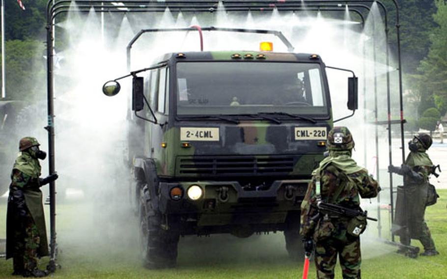 A vehicle goes through a portable car wash as the first phase of decontamination during a chemical-attack-response exercise Tuesday at Camp Casey, South Korea.