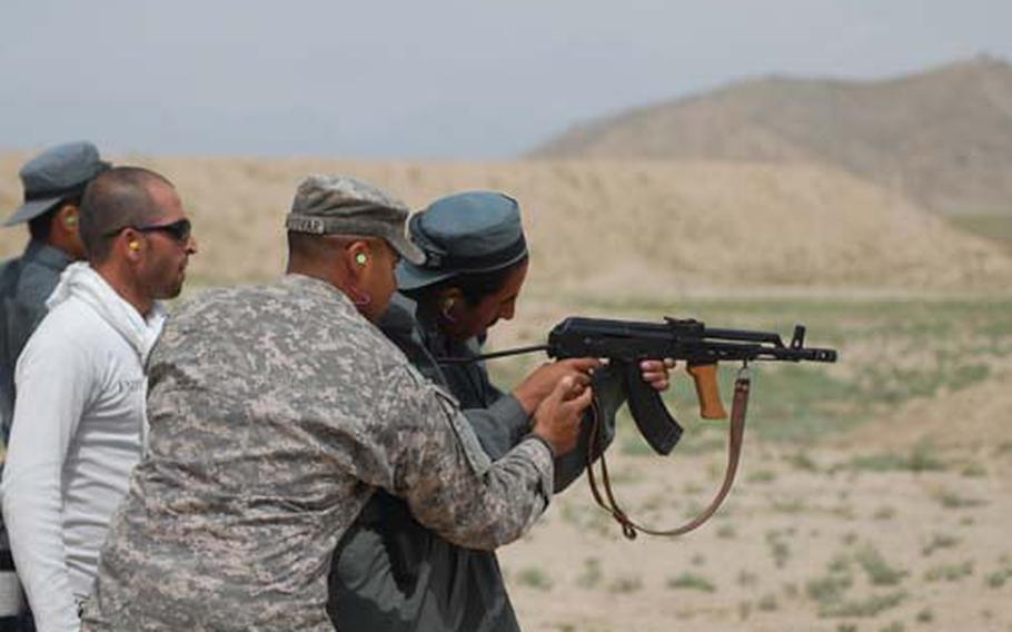 Staff Sgt. Joshua Almodovar of Chicago, with the National Guard’s 33rd Brigade Combat Team, instructs a new Kabul police recruit as he fires an assault rifle.