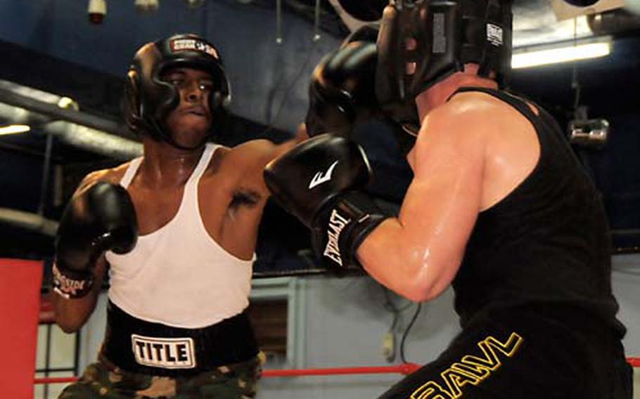 Sgt. Derek Woodard, left, with 1st Battalion, 1st Special Forces Group, swings at Sgt. Kellan Willis, 58th Signal Battalion, during a boxing smoker at Tenkaichi Stadium in Chatan Thursday. Woodard won the match.