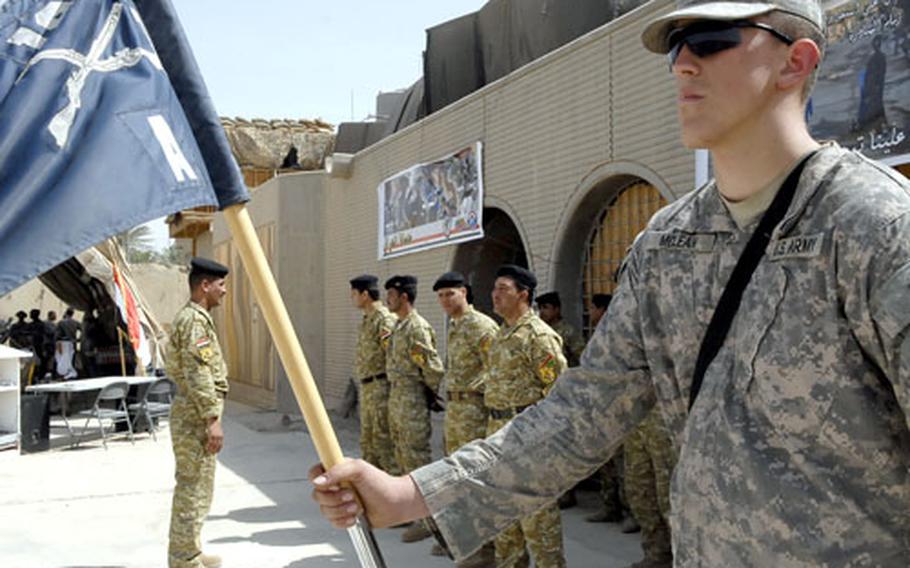 A U.S. soldier stands at attention while his Iraqi counterparts wait for the official handover of Joint Security Station Hurriyah 1 in northwest Baghdad.