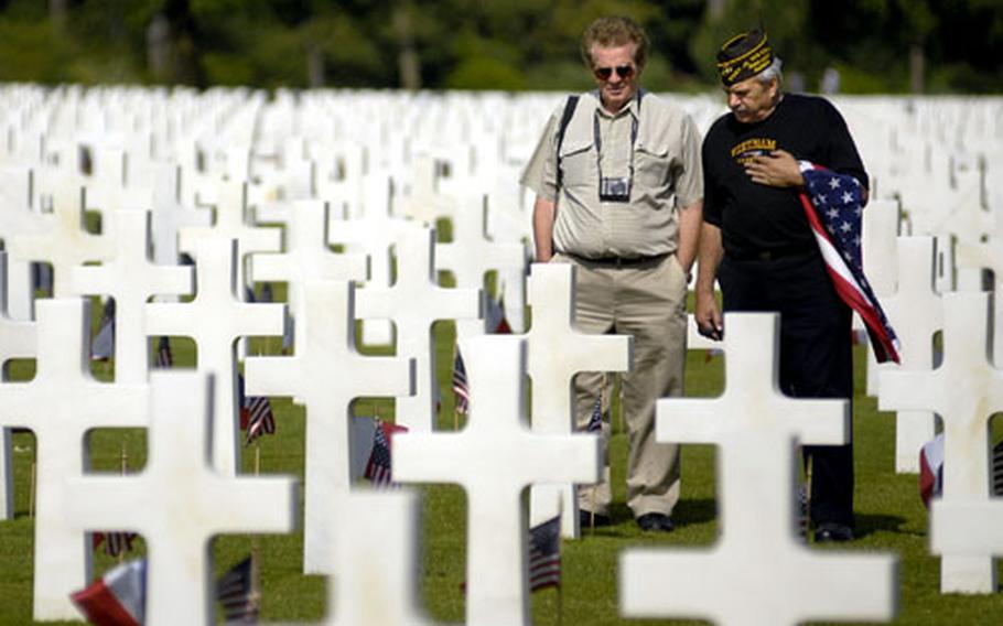Larry Cavanaugh, right, and his cousin, Don Henry, make their way through the Normandy American Cemetery Friday near Colleville-sur-Mer, France. Cavanaugh traveled from Chicago to visit the site on the 40th anniversary of returning from Vietnam, where he served in the Marines. While at the cemetery, Cavanaugh was given the opportunity to raise and lower the U.S. flag there.