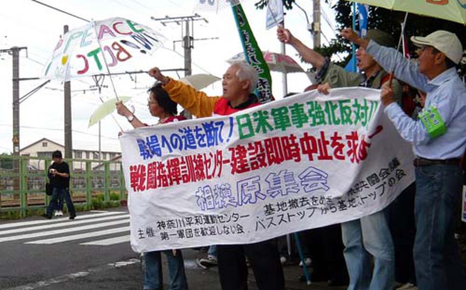 Protesters raise their fists Saturday, expressing their opposition against the construction of U.S. Army’s Battle Command Training Center in front of Sagami General Depot.
