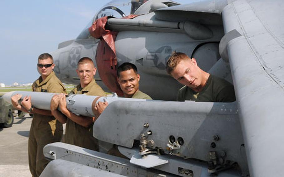 Marines with Marine Fighter Squadron 211, based at Yuma, Ariz., and deployed to the 31st Marine Expeditionary Unit, load a 340-pound AIM-120 advanced medium-range air-to-air missile under the wing of an AV-8 Harriar at Kadena Air Base.