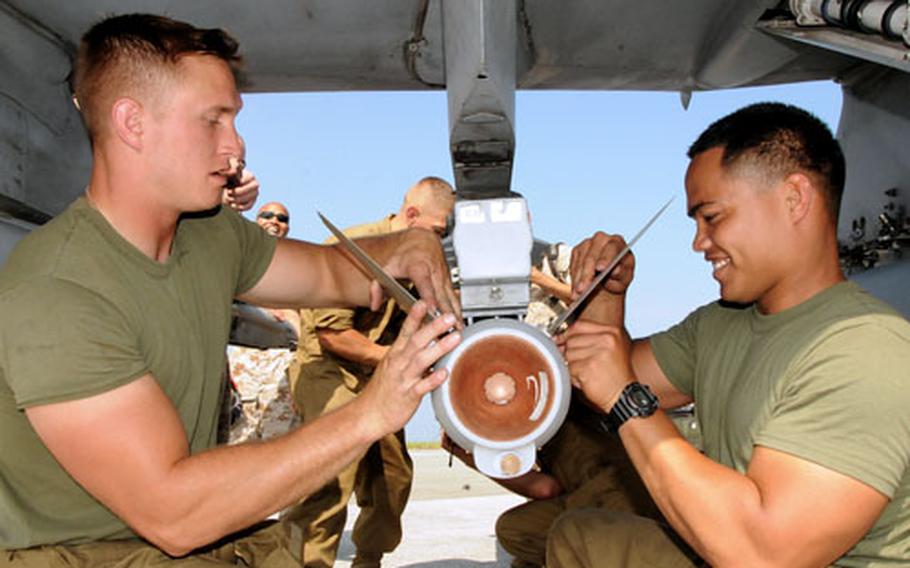 Cpls. Jerry Bennet, left, and Ricky Babauta, both with Marine Fighter Squadron 211, attach the fins to an AIM-120 advanced medium-range air-to-air missile Monday at Kadena Air Base.