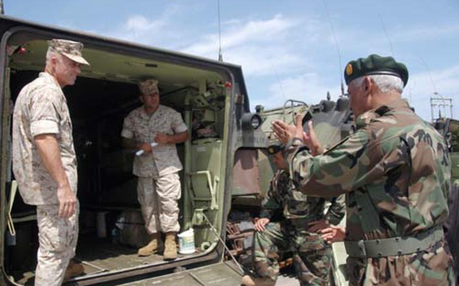 Col. Jeff Haynes, a 3rd Marine Division staff officer, left, Cpl. Oscar Ramirez, an Amphibious Assault Vehicle crewman with the Combat Assault Battalion, 3rd Marine Division, center, answer questions from Maj. Gen. Rahim Wardak, right, of the 201st Corps of the Afghan National Army Wednesday at Camp Schwab during a tour of AAVs. Wardak and delegates from the 201st Corps were touring Marine bases to familiarize themselves with equipment and operations.