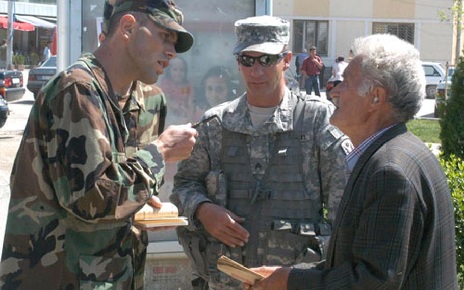 Translator Blerim Sadiku and Sgt. Robert Meggitt talk to a local resident during a patrol in the city of Vitina, Kosovo. The man had his tractor stolen in 2000 and was hoping to receive word on how to get a replacement.