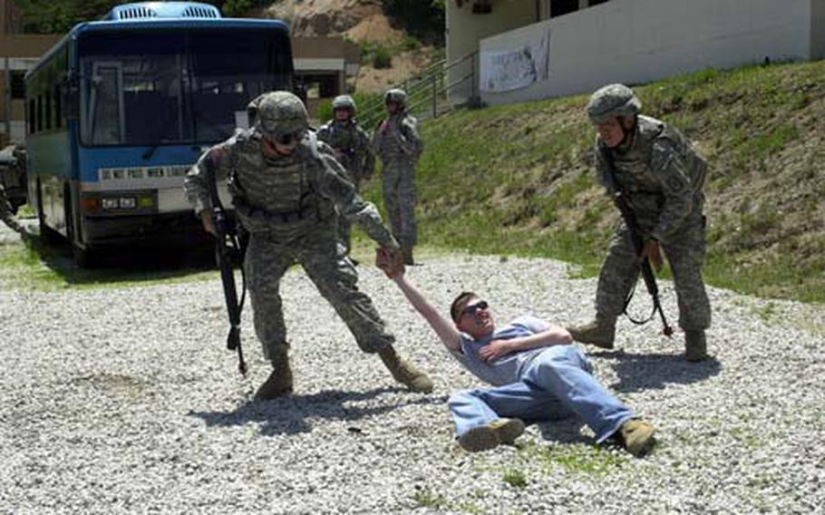 Military police pull an injured civilian to safety as snipers interupt the evacuation of an apartment building during a training exercise.