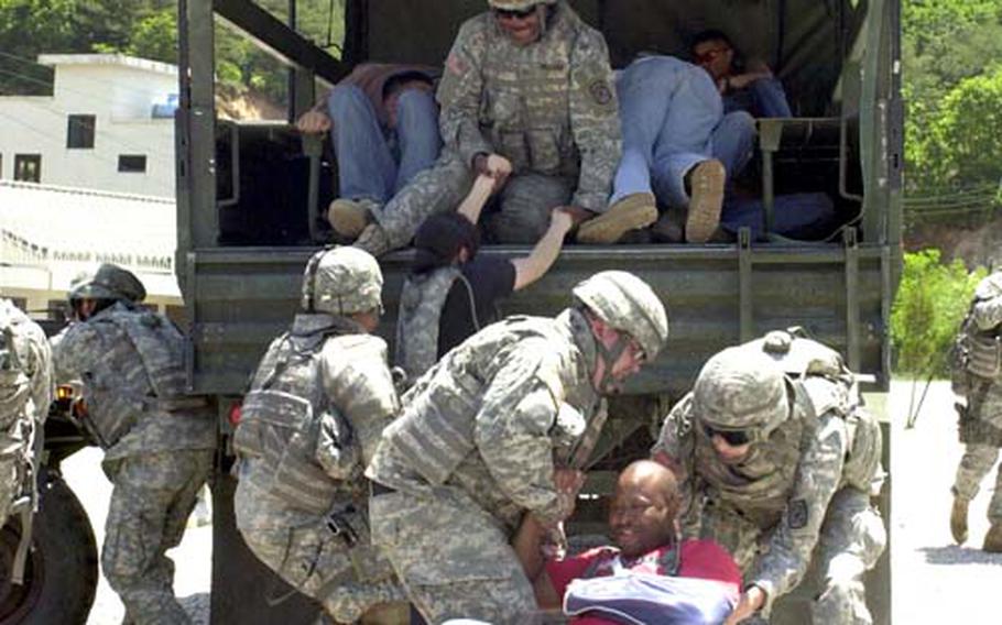 Military police load apartment building evacuees into a truck under sniper fire during a training exercise.