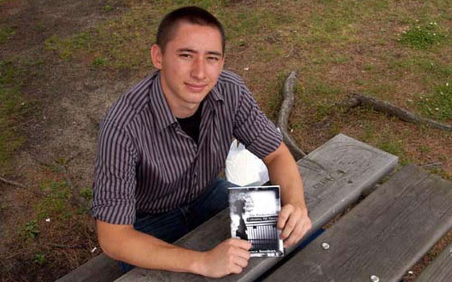Terence Sanders displays a proof copy of his new book, “The Pocketbook: Coloring the Gray,” while visiting Yokosuka Naval Base, Japan, on Tuesday. Sanders, a first-year student at Tulane University, based some of the personality traits of his characters on people he met as a student at Kinnick High School.