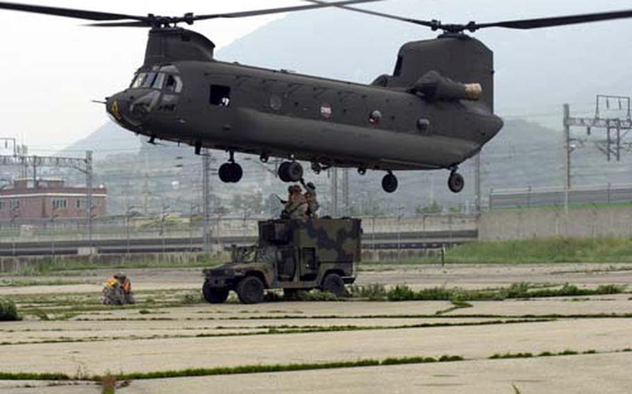 A vehicle is attached to the underbelly of a Chinook helicopter during a sling-load training exercise Tuesday at Camp Mobile.