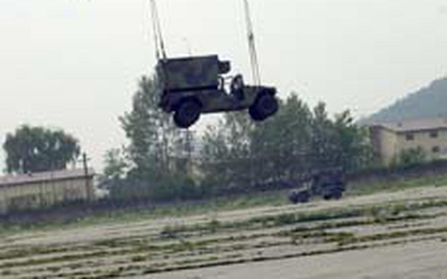 Members of the 304th Integrated Theater Signal Battalion look on as a Chinook helicopter heads back to Camp Humphreys.
