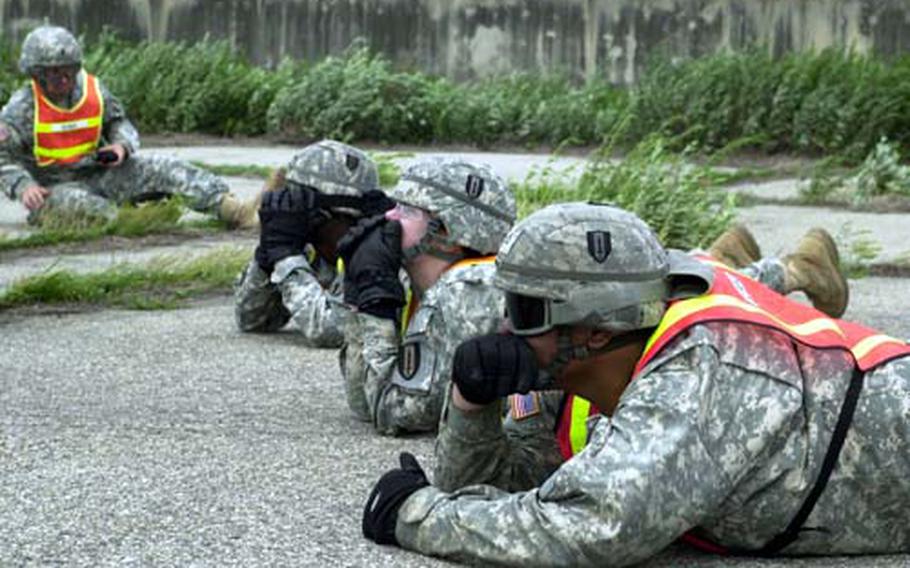 Members of the 304th Integrated Theater Signal Battalion shield their faces from flying debris as they watch a Chinook fly away.