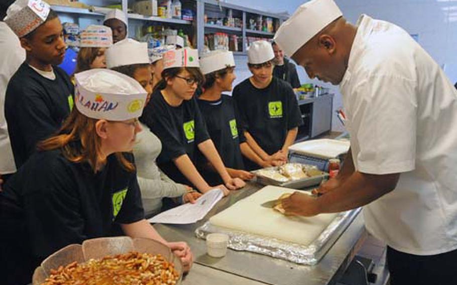 Students in the culinary arts class watch chef Sgt. 1st Class Howard Shakespear prepare a dish.