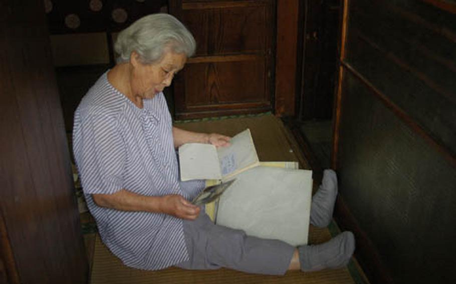 Suzu Kuriha looks at pictures and documents from the Japanese Imperial Military Academy at Sobudai, during a visit to her home by U.S. Army Japan officials. Kuriha served as the secretary to the commandant of the academy from April to September of 1945.
