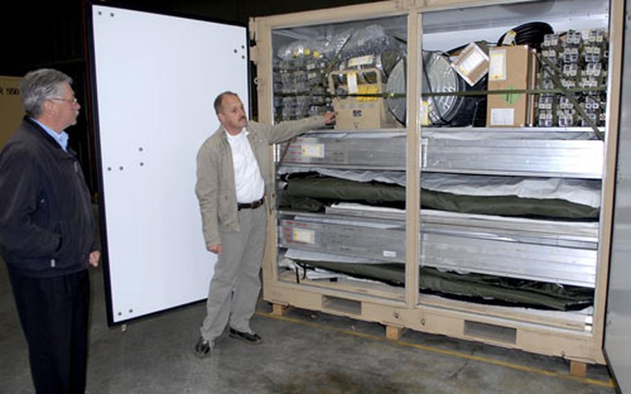 Marco Holtzem, left, manager of the U .S. Air Forces in Europe Central Region Storage Facility, and Paul Weckering, operations chief for the Warehouse Services Agency, stand in front of a billeting container that’s part of the Air Force’s basic expeditionary airfield resources package.