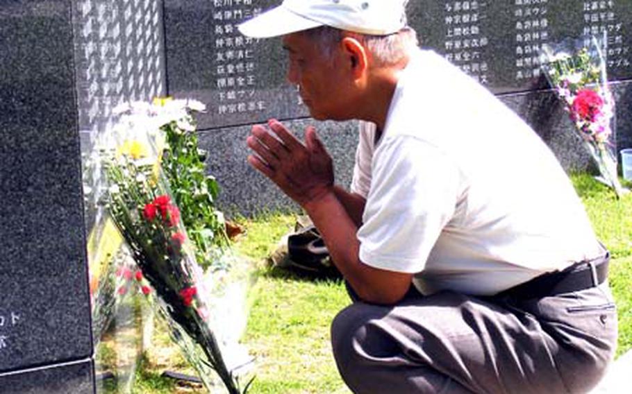 Masakazu Miyagi, 74, prays at the section of a wall in Peace Prayer Park that features the name of a relative killed during the Battle of Okinawa.
