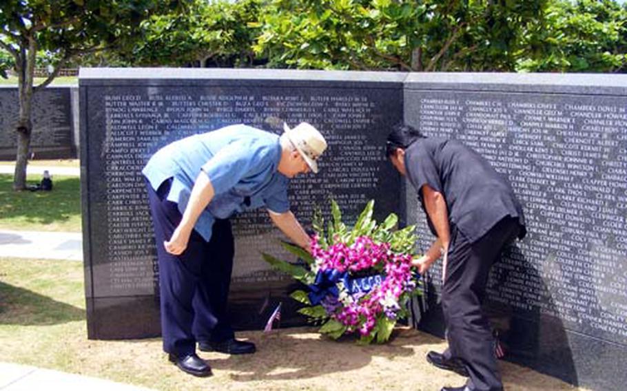 Joe Thompson, former president of the American Chamber of Commerce on Okinawa, and Tony Sakuda, the chamber’s current vice president, lay a wreath at the memorial wall in Peace Prayer Park on Tuesday.