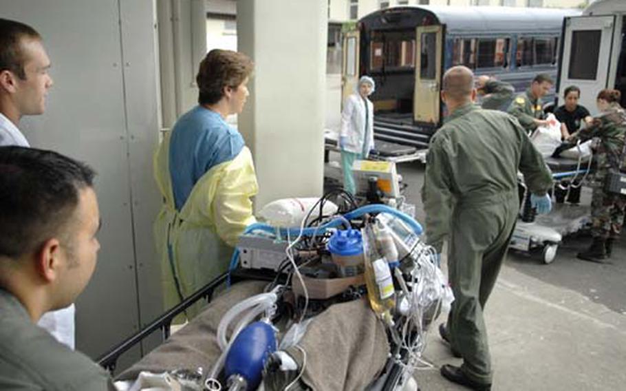 Army Capt. Karla Clarke, center, an ICU nurse at Landstuhl Regional Medical Center, assists in transporting her patient to a bus for air transport Aug. 21, 2007. The Defense Department is looking at building an Army hospital on Ramstein Air Base instead of moving ahead with plans to construct an inpatient tower at LRMC.