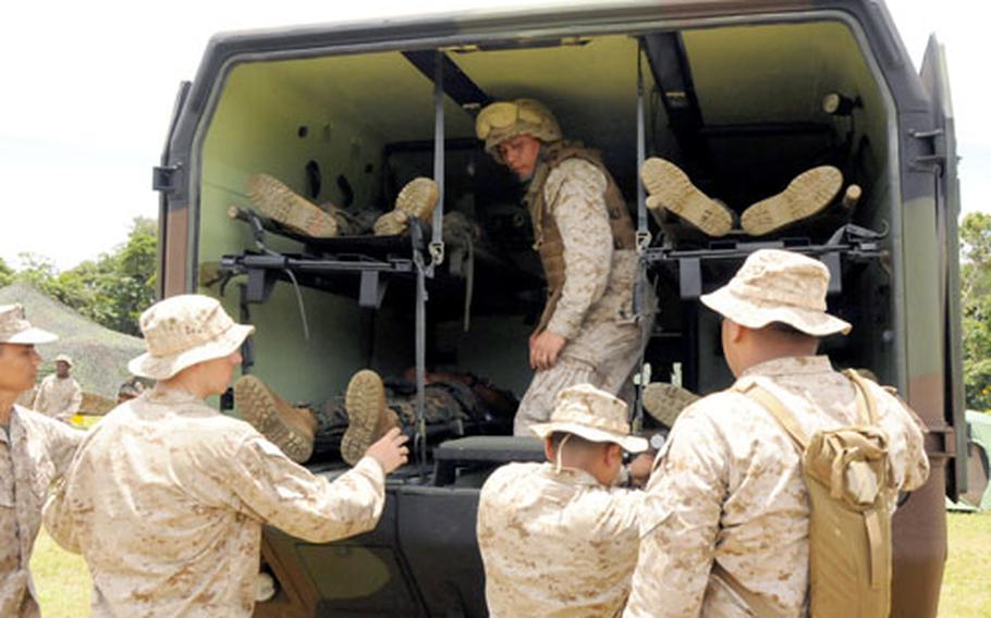 In the back of an ambulance at Landing Zone Whippoorwill, the site of a forward resuscitative suite, Petty Officer 3rd Class Michael Gandionco directs which simulated victims should be unloaded first Thursday during 3rd Medical Battalion&#39;s Solar Challenge exercise. The victims were then taken to a triage area, then pre-op, next the operating room and finally a recovery area. The suite also had a tent set up for blood work and x-rays.
