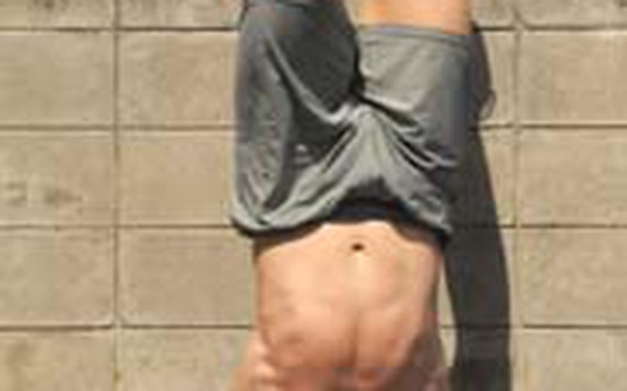 1st Lt. Rob Gerdes strains to complete 12 handstand push-ups Tuesday as part of his workout at CrossFit Asia, a gym in Okinawa City. The workout consisted of three sets of a 400-meter dash, 21 kettle-bell lifts and 12 handstand push-ups. Gerdes finished in 10 minutes, 9 seconds.