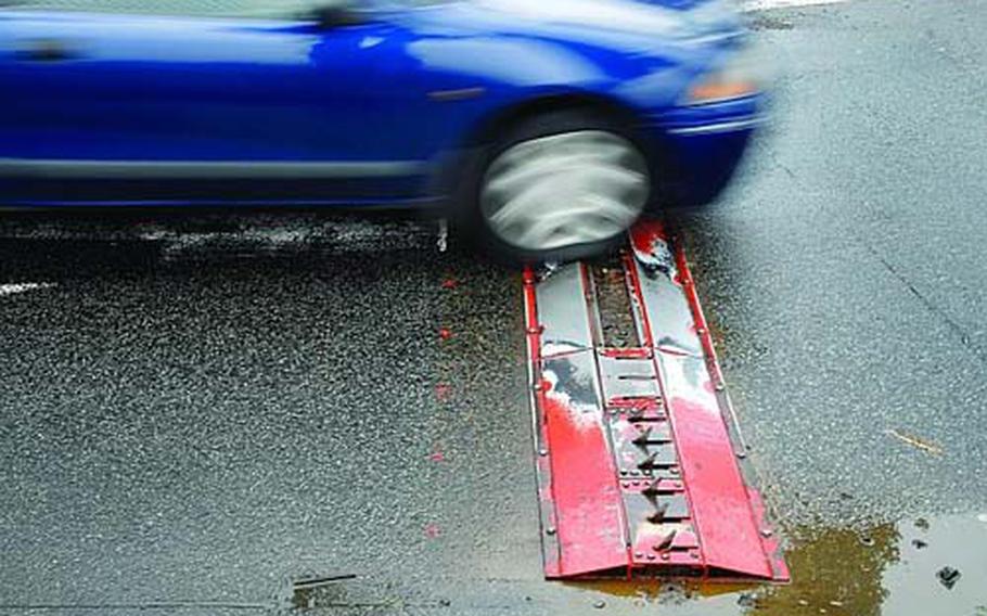 A vehicle bumps over an old, broken tire shredder May 15 at an exit in Vogelweh, Germany. The Air Force has removed tire shredders from exits on its bases throughout the Kaiserslautern military community.