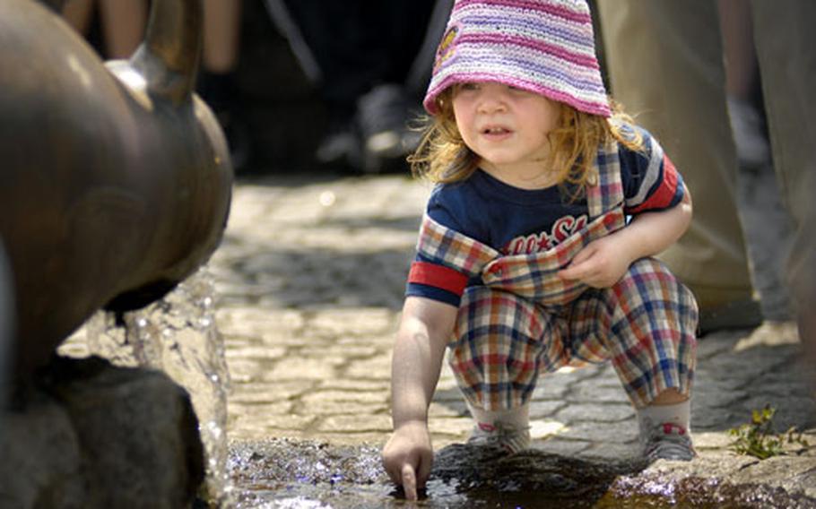Lucille Kennedy, 2, checks out a water fountain in the center of Binsfeld before going on a hike through the town and the surrounding countryside Thursday.