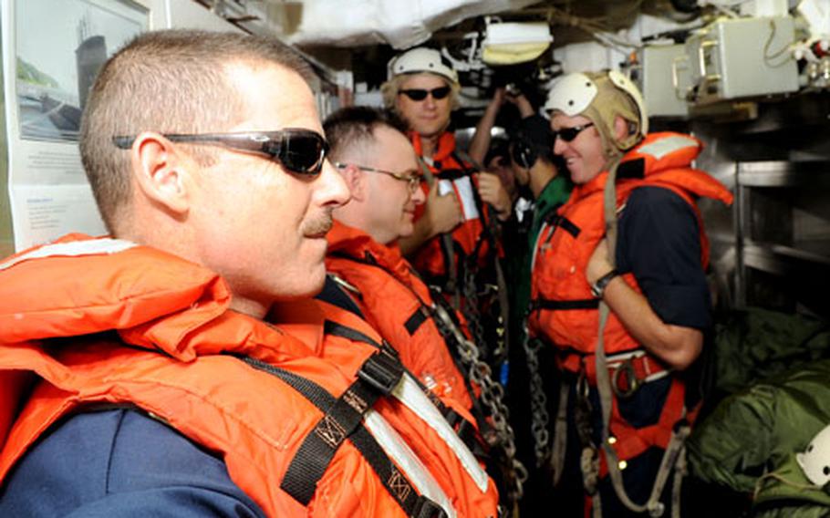 Senior Chief Robert Muegge, left, and other sailors prepare to go topside.