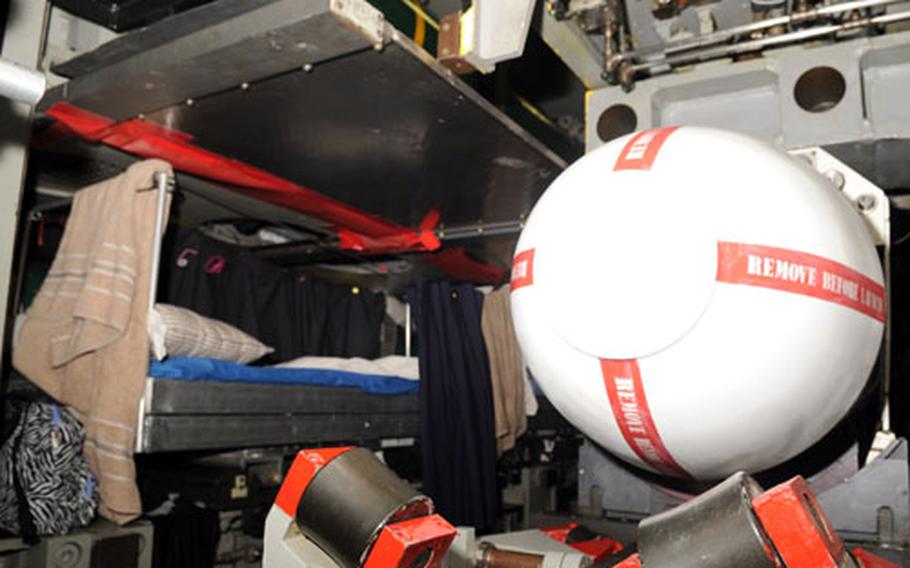 Torpedomen aboard the USS Seawolf sleep near their weapons, like the Tomahawk missile to the right.