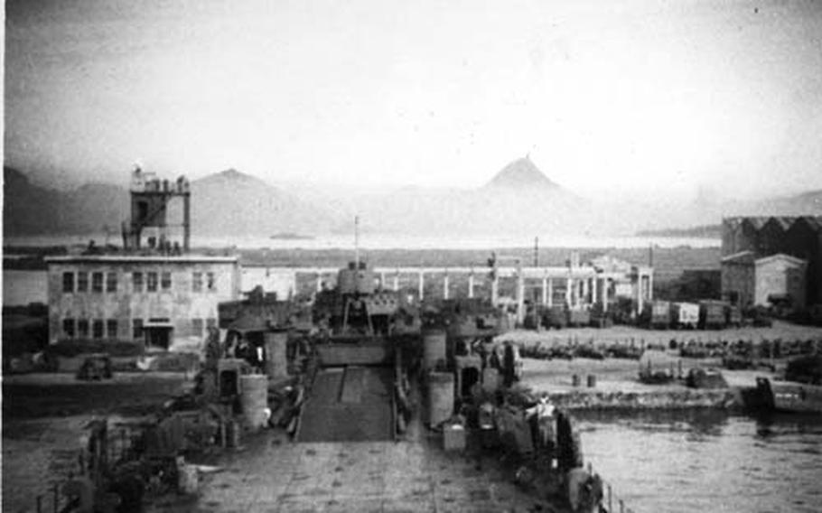 Aug. 29, 1945 USS LST 1077 makes landfall at Sakibe in Sasebo in August 1945. The peak of Mt. Akasaki rises from the haze along the horizon.