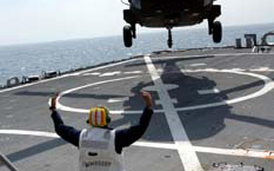 A U.S. Army Blackhawk helicopter from Camp Zama, Japan, hovers down to the landing deck of the destroyer USS Curtis Wilbur.