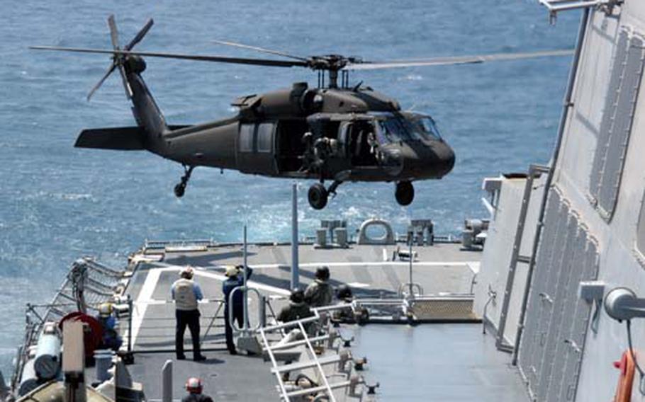 A U.S. Army UH-60A Blackhawk helicopter descends to the landing deck.