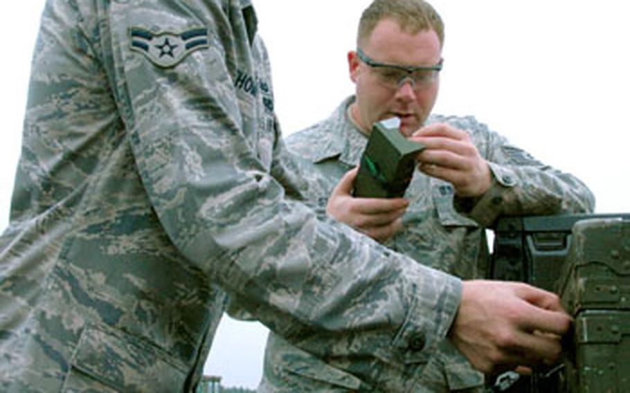 Airman 1st Class Matthew Thompson, left, and Tech. Sgt. Rory Stark work on preparing remote firing devices during a clean-up mission on Draughon Range.
