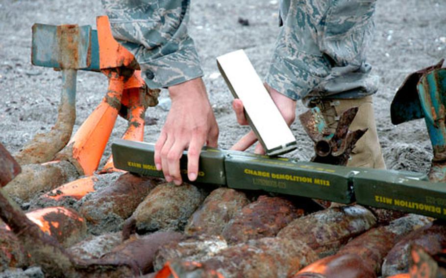 An explosive ordnance disposal tech lays bricks of C-4 explosives between old dummy training bombs during an annual clean-up on Draughon Range, near Misawa Air Base, Japan, on Friday. The C-4 was used to explode dummy training bombs that had not discharged their marking charges — about the same strength as a shotgun blast — upon impact at the range.