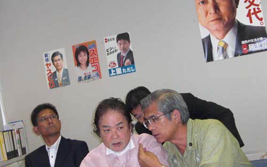 Shoukichi Kina, center, leader of the Okinawa chapter of the Democratic Party of Japan, consults with other party leaders prior to a news conference Tuesday after meeting with Okinawa Gov. Hirokazu Nakaima. The local chapter of the party that swept the Liberal Democratic Party out of power Sunday wants to quash the plan to build a new Marine air facility on Okinawa.