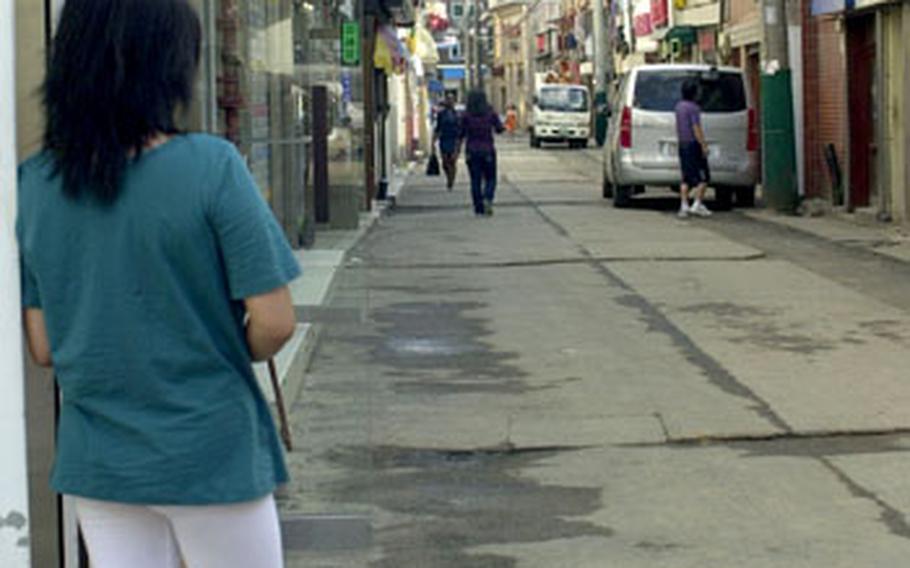 Jenny, left, looks down one of the main roads in The Ville, an area outside Camp Casey in South Korea where she worked at one of the juicy bars and says she was pressured to prostitute herself. She is now three months pregnant and says the father of her unborn child, a U.S. soldier, has abandoned her. "No matter how many problems, or how big the problems that come to me, I have to be strong,” she said.